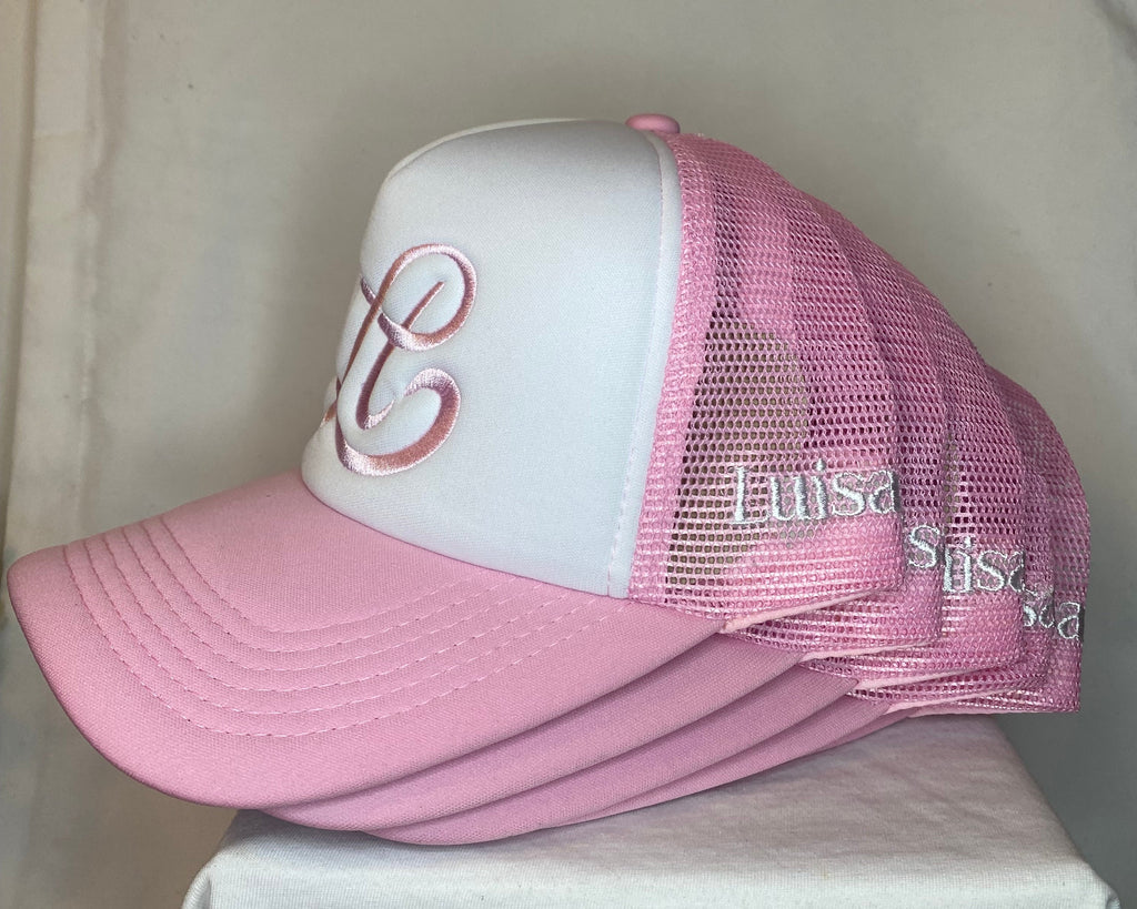 Pink and white baseball cap with mesh back on a white surface