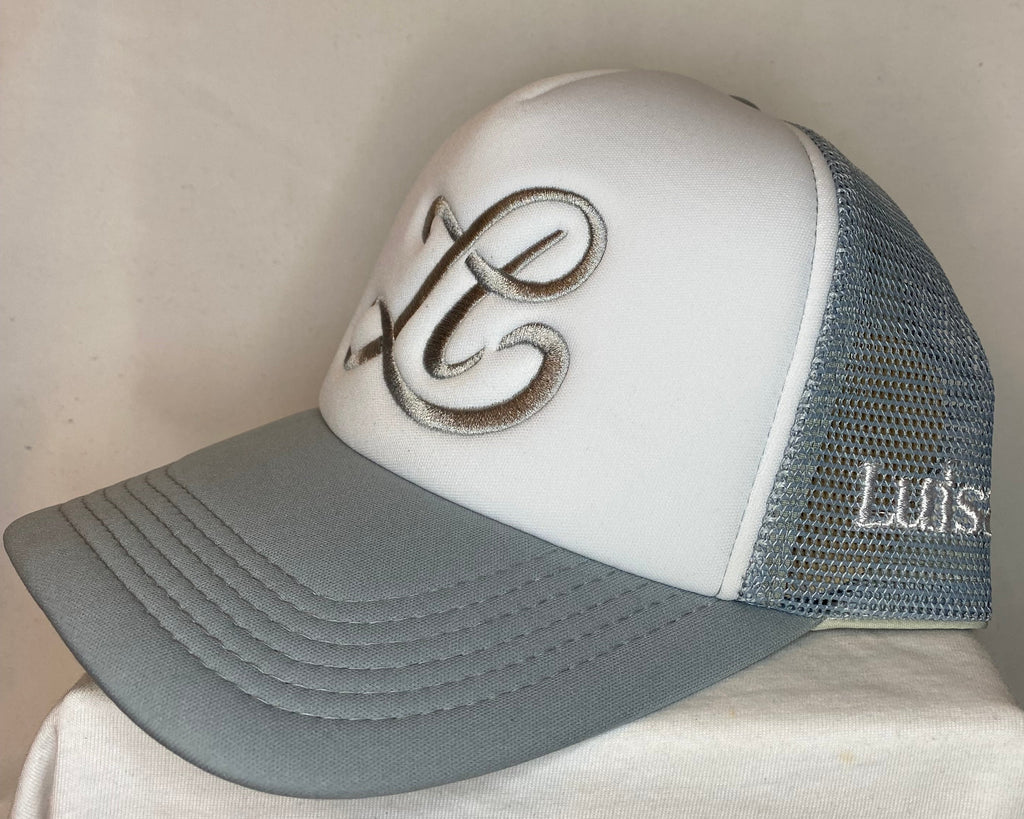 White and gray cap with embroidered design on a beige background